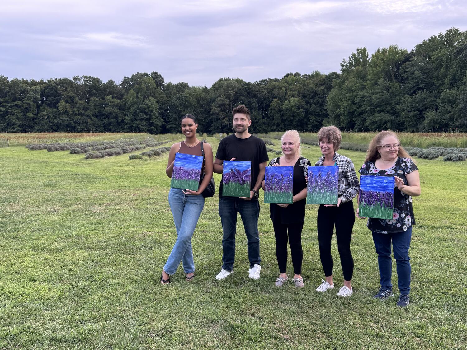 Kids proudly holding up their finished paintings at a Bravaura art party