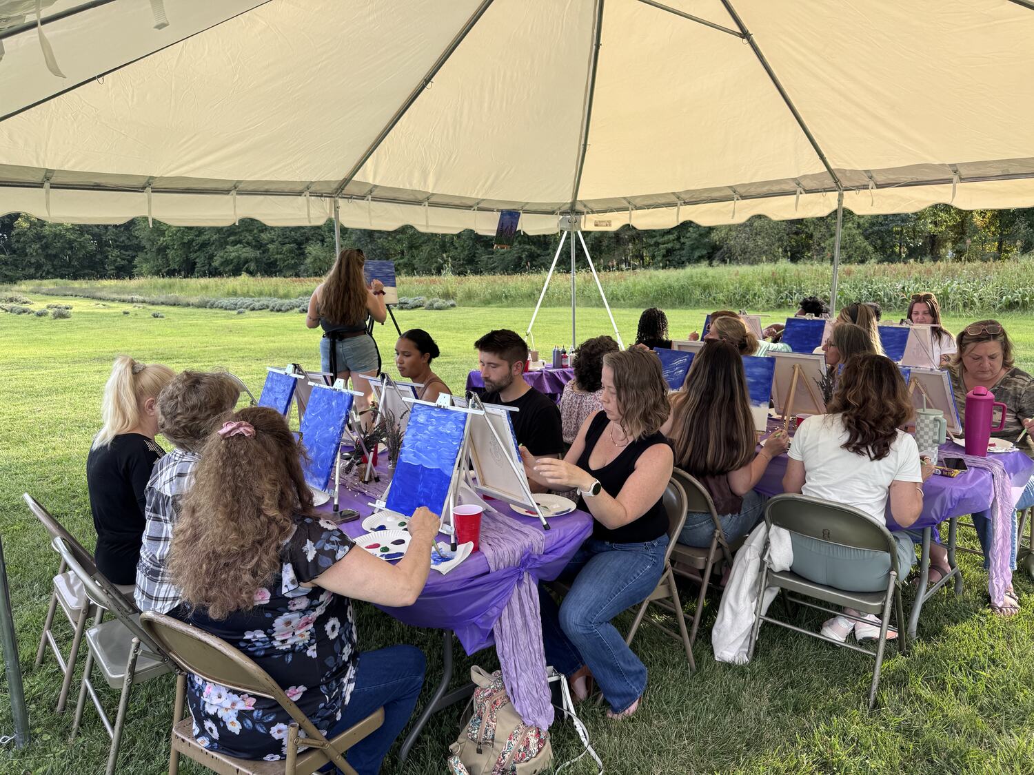A long table of painters under the tent at the lavender farm